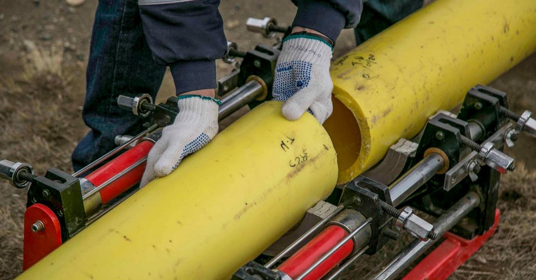 Plumbers fitting a large yellow pipe